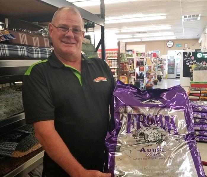 A purple bag of dog food being held by a SERVPRO employee