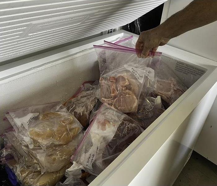 hand pulling frozen food out of full chest freezer