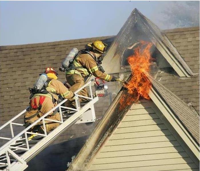 Firefighters climbing ladder to roof to extinguish blaze