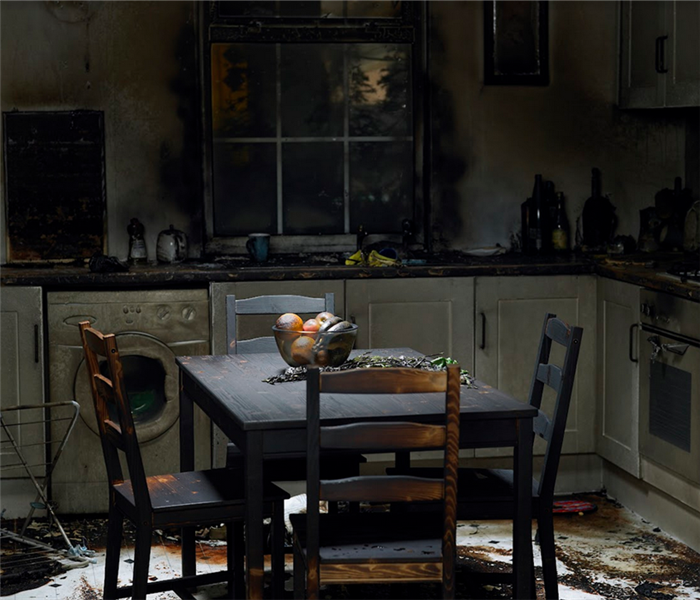 a fire damaged kitchen with soot covering the tables, counters and walls