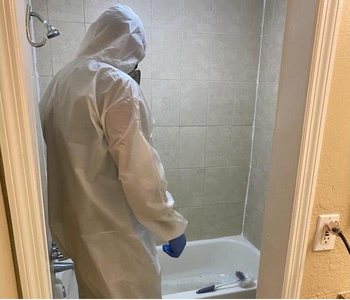 SERVPRO employee in PPE in a mold damaged bathroom