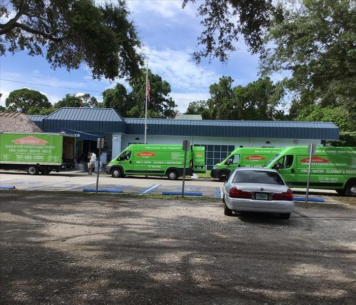 Water Damaged Building with SERVPRO Trucks Outside