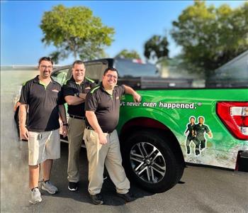 three SERVPRO employees leaning against a truck